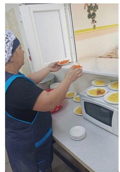 Повар на раздаче раздаёт салаты школьникам
